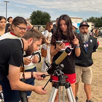 People looking though a solar telescope.